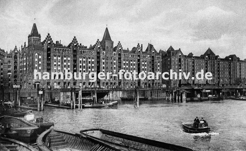 01147734 altes Hamburg Fotos - Blick ber den Brooktorhafen zu den Speicherblcken V + X. Schuten und Khne liegen an der Kaimauer oder den Holz Duckdalben. Eine kleine Barkasse fhrt durch das Hamburger Hafenbecken Richtung Magdeburger Hafen. 