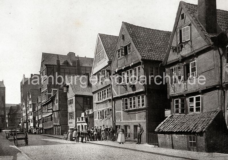 0122_017_1_9 Wohngebude am Brooksgraben - die Einwohner der historischen Fachwerkhuser stehen auf dem gepflasterten Fussweg. Die Frauen und Mdchen tragen weisse Schrzen - auf der Strasse sind Handwagen und Karren abgestellt. Ab 1883 wurden die Wohnviertel auf den Elbinseln Kehrwieder und Wandrahm abgerissen, um die Speicherstadt zu errichten. Etwa 20 000 Menschen wurden zwangsumgesiedelt und ca. 1100 Huser zerstrt.