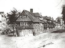 0129_030_133 Fachwerk-Wohnhuser in der Dienerreihe - die Gebude wurden fr die Ratsdiener errichtet; rechts im Hintergrund der Turm der ehemaligen St. Annen Kapelle. Links stehen leere Holzfuhrwerke am Strassenrand. Ab 1883 wurden die Wohnviertel auf den Elbinseln Kehrwieder und Wandrahm abgerissen, um die Speicherstadt zu errichten. Etwa 20 000 Menschen wurden zwangsumgesiedelt und ca. 1100 Huser zerstrt.