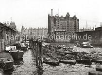 0155_228_2 Blick von der Baakenbrcke auf den Magdeburger Hafen - Schuten und Binnenschiffe liegen am Kai unter den Winden der Fruchtschuppen. Am Bug eines der Lastkhne ist das Logo der Hamburg - Sdamerikanische Dampfschifffahrts-Gesellschaft H.S.D.G. angebracht und an der Bordwand eines anderen Schiffs ist der Schriftzug "Hamburg Amerika Linie" zu erkennen. An den Dalben des Hafenbeckens wird Schrott in Schuten gelagert, ein Arbeitsschiff fhrt unter Dampf Richtung Magdeburger Brcke; rechts der Kaispeicher B, davor das Brckenwrterhaus - im Hintergrund die Speicherblcke am Brooktorkai. 1868 wurde als erstes knstliches Hafenbecken der Sandtorhafen ausgehoben. Die neugeschaffenen Kaianlagen des nrdlichen Sandtorkais bestanden aus hlzernen Bollwerken, spter beim 1872 fertiggestellten Kaiserkai aus  Klinkern, an der die Seeschiffe direkt anlegen konnten. Sie verfgten meistens ber parallel zur Kaikante auf Schienen bewegliche Krananlagen fr den Stckgutumschlag, ber Eisenbahnanschluss sowie einfache Kaischuppen, die dem Sortieren, nicht aber dem Lagern von Waren dienten. Dies ermglichte zum ersten Mal einen direkten Warenumschlag in Bahnwaggons oder Fuhrwerke und galt seinerzeit als das modernste Umschlagsystem der Welt. Binnen weniger Jahre erfolgte der Bau weiterer Hafenbecken auf dem Groen Grasbrook, so des (1876), des Magdeburger Hafen (ab 1872) und des Brooktorhafen (um 1880) mit einem Durchlass zwischen beiden, 1881 kam der Grasbrookhafen hinzu.