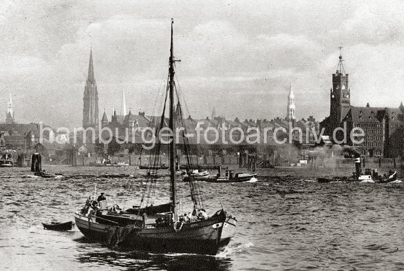 0172_236_2a Ein Fischkutter fhrt auf im Hamburger Hafen - der Steuermann des Schiffs steht im Heck; im Schlepp hat der Kutter ein Ruderboot,  Netze hngen ber die Bordwand des Holzschiffs. Auf der Norderelbe fahren Barkassen und ein Schlepper; schwarzer Qualm kommt aus dem Schornstein des Arbeitsschiffs. Im Hintergrund Kirchtrme der Hansestadt, sowie Rathausturm und die Neogotischen Giebeltrme der Speicherstadt - rechts der Uhrenturm des Kaiserspeichers - in seinem inneren befindet sich eine feuersichere Treppe, die eine Fluchtmglichkeit beim Brand in dem Lagergebude bietet.