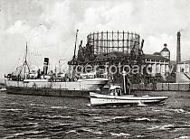 0174_237_76_2 Ein Schlepper mit hohem Schornstein berquert die Elbe beim Gaswerk Grasbrook - ein Frachtschiff hat im Strom an den Dalben fest gemacht. Im Hintergrund die Krananlagen am Kai des Hamburger Gaswerks auf dem Grasbrook.  Die Gaswerke wurden dort 1844 als Privatgesellschaft gegrndet, 1845 bei einer Sturmflut zerstrt und 1846 wieder aufgebaut. 1874 ging die Anlage in den Besitz der Stadt ber. In den vier Gasbehltern  knnen insgesamt 73 000 cbm Gas gespeichert werden. Das grte Gasometer hat einen Durchmesser von 56m - es kann 50 000 cbm speichern. Die Kohle wird von Seeschiffen gebracht, die direkt am Kai des Gaswerks mit einem hydraulischen Kran entladen werden. In neun Kohlenschuppen knnen ca. 30 000 t Kohle auf dem Gelnde der Gasanstalt Grasbrook gelagert werden.