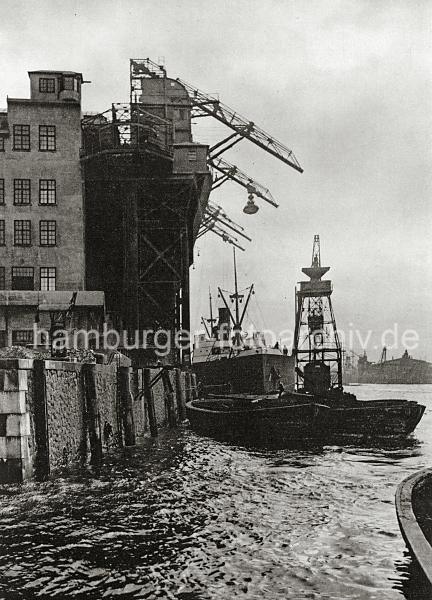 0176_18_2 Krananlage am Kai der Gasanstalt auf dem Grasbrook - Ewerfhrer stossen ihre Schuten mit dem Peekhaken von der gemauerten Kaiwand ab. Im Hintergrund arbeitet ein schwimmender Kohlenheber neben einem Dampfschiff.  In neun Kohlenschuppen knnen ca. 30 000 t Kohle auf dem Gelnde der Gasanstalt Grasbrook gelagert werden.