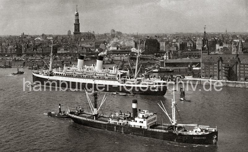 0180_224_82 Ein Passagierschiff hat an den Dalben vor dem Kaispeicher A festgemacht; eine Gangway ist am Heck des Dampfers herunter gelassen - sie fhrt zu einer Barkasse. Ein Frachter fhrt mit Schlepperuntersttung zu einem der Hafenbecken. Hinter der Einfahrt zum Sandtorhafen und der Kehrwiederspitze das Hamburg Panorama mit der St. Michaeliskirche; im Bildzentrum die Haltestelle Baumwall.