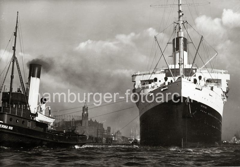 0183_224_84 Das Passagierschiff Cap Arcona luft aus dem Hamburger Hafen aus - Hafenschlepper untersttzen das ca. 200m lange und 25m breiten Passagierdampfer bei der Ausfahrt. Das Dampfschiff hat eine Besatzung von 630 Personen und kann ursprnglich 1315 Passagiere an Bord nehmen. Zwischen den Trossen der Schlepper ist das Speichergebude und der Uhrturm des Kaispeichers A am Kaiserhft zu sehen; rechts davon die Einfahrt zum Grasbrookhafen.