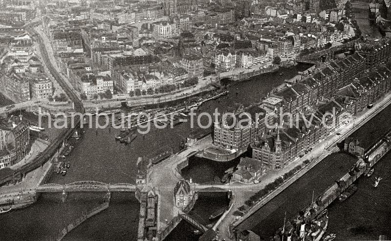 0186_237_73_2 Blick auf die Hamburger Speicherstadt und den Binnenhafen; links im Vordergrund die Niederbaumbrcke und die Hochbahnhaltestelle BAUMWALL. Vorne rechts die Kaischuppen am Sandtorkai, ein Dampfer liegt am Kai.