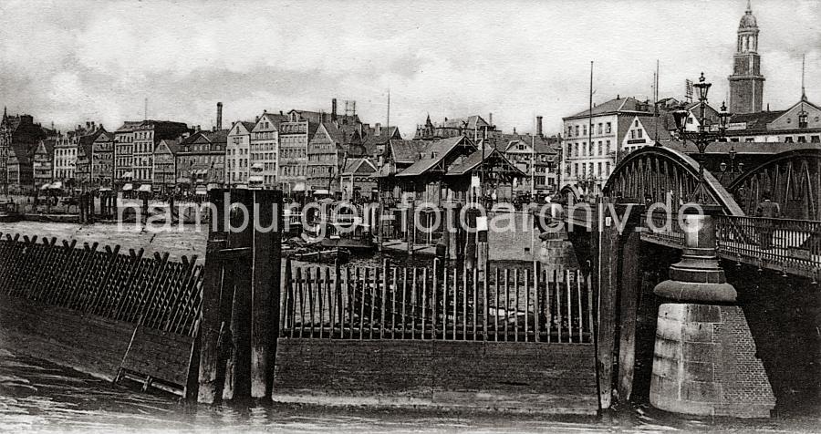 0191_225_2 Der Zollzaun im Vordergrund sichert das Freihafengelnde gegen Schmuggel und die Ausfuhr von unverzollten Waren. Ein Schlepper hat gerade die Niederbraumbrcke unterfahren - dahinter der Anleger am Baumwall mit Hafenfhren und Wartehuschen. Die Ladengeschfte am Baumwall schtzen ihre Auslagen mit Markisen gegen die Sonne.