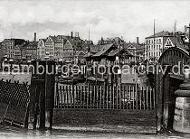 0191_225_2 Der Zollzaun im Vordergrund sichert das Freihafengelnde gegen Schmuggel und die Ausfuhr von unverzollten Waren. Ein Schlepper hat gerade die Niederbaumbrcke unterfahren - dahinter der Anleger am Baumwall mit Hafenfhren und Wartehuschen. Die Ladengeschfte am Baumwall schtzen ihre Auslagen mit Markisen gegen die Sonne.