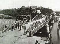 0192 Niederbaumbrcke vom Baumwall zum Kehrwieder; rechts im Hintergrund einer der Kaischuppen am Sandtorhafen. Links die Wohn- und Gewerbegebude am Kehrwieder; Schuten und Arbeitsschiffe liegen im Wasser.