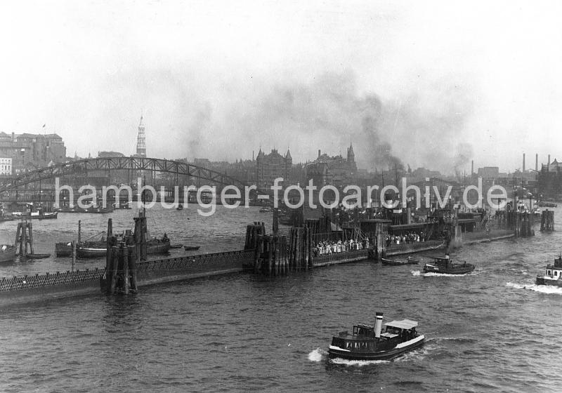 0195_223_06 Ponton in der Elbe beim Baumwall; Ausflgler stehen dicht gedrngt auf dem Anleger und warten auf das Ausflugsschiff. Im Hintergrund die Neugotischen Trme der Speicherstadtblcke - rechts die Einfahrt zum Sandtorhafen, dahinter die Schornsteine vom Gaswerk auf dem Grasbrook.