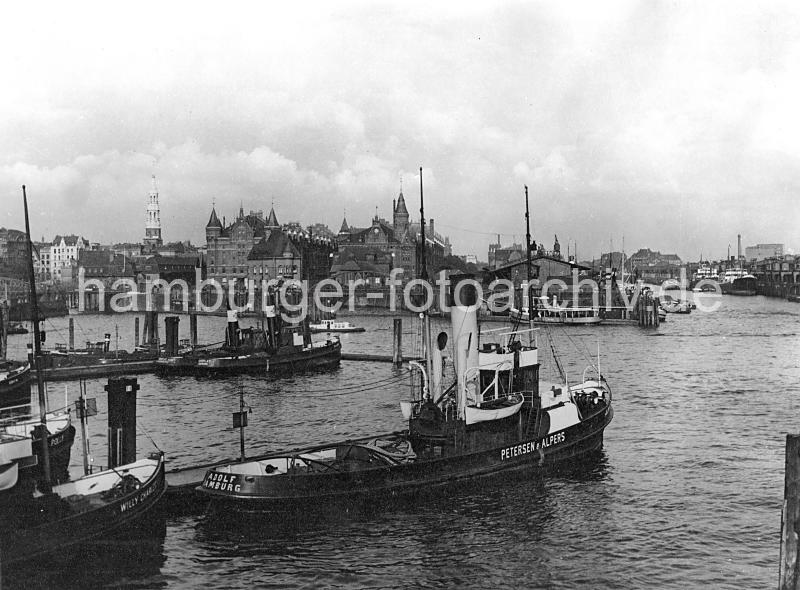 0196_223_07 Schlepper an ihrem Liegeplatz am Baumwall; im Hintergrund die Speicherblcke J + K, die zu beiden Seiten des Kehrwiederfleet legen. Rechts die Einfahrt zum Sandtorhafen - Frachtdampfer liegen am Kaiserkai. Am Sandtorhft hat eine Barkasse angelegt - links der Kirchturm der St. Katharinenkirche.