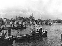 0196_223_07 Schlepper an ihrem Liegeplatz am Baumwall; im Hintergrund die Speicherblcke J + K, die zu beiden Seiten des Kehrwiederfleet legen. Rechts die Einfahrt zum Sandtorhafen - Frachtdampfer liegen am Kaiserkai. Am Sandtorhft hat eine Hafenfhre angelegt - links der Kirchturm der St. Katharinenkirche.