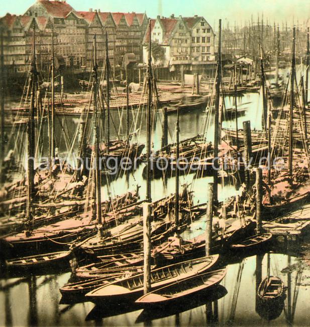 0199 Dicht an dicht liegen die Ewer und Schuten an den Holzstmmen im Binnenhafen. Mehrstckige Wohnhuser stehen auf dem Kehrwieder; am Kai sind mit Holz abgedeckte Winden zu erkennen, mit denen die Last an Land gehievt wird. Im Hintergrund die Masten der Segelschiffe im Jonashafen.