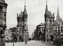 0203_222_04b Zollstation mit Giebeltrmen auf der Freihafenseite der Brooksbrcke; Pferdefuhrwerke passieren mit ihrer Ladung die Brcke, Fussgnger gehen durch den schmalen Torweg - Schilder weisen auf die Zollgrenze hin. Im Hintergrund Geschftshuser Bei den Mhren und der neogotische Turm der St. Nikolai Kirche.