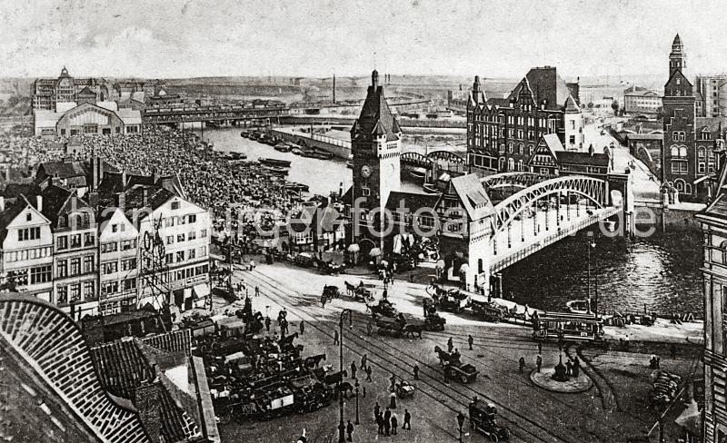 0225_237_81_1 Eingespannte Zugpferde stehen mit ihren Fuhrwerken auf dem Messberg, die Kutscher warten auf der Strasse auf eine Fuhre. Auf der Wandrahmsbrcke ber dem Zollkanal warten die Pferdefuhrwerke; die Marktflche auf dem Gemsemarkt ist mit Hndlern und Kunden dicht gefllt. An den Kais des Oberhafen liegen die Schuten und Lastkhne in mehreren Reihen. Im Hintergrund die Oberhafenbrcke und die Gemsehalle.