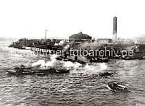 0246_XII_115 Ein Schleppverband kommt aus dem Magdeburger Hafen und berquert die Norderelbe - Binnenschiffe liegen bei den Schuppen des Magdeburger Hafens. Dahinter das Gelnde der Gaswerke auf dem Grasbrook mit Gasometer und hohem Schornstein.  Das Gaswerk auf dem Grasbrook wurde 1844 als Privatgesellschaft gegrndet, schon 1845 bei einer Sturmflut zerstrt und 1846 wieder aufgebaut. 1874 ging die Anlage in den Besitz der Stadt ber. In den vier Gasbehltern  knnen insgesamt 73 000 cbm Gas gespeichert werden. Das grte Gasometer hat einen Durchmesser von 56m - es kann 50 000 cbm speichern. Die Kohle wird von Seeschiffen gebracht, die direkt am Kai des Gaswerks mit einem hydraulischen Kran entladen werden. In neun Kohlenschuppen knnen ca. 30 000 t Kohle auf dem Gelnde der Gasanstalt Grasbrook gelagert werden.