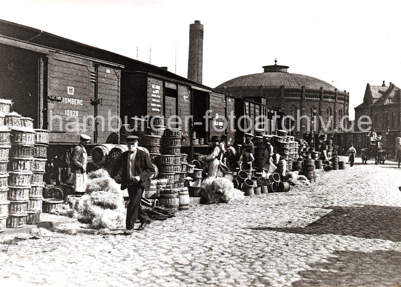 0247_XII_145 Gterwaggons aus dem der polnischen Stadt Bromberg stehen auf einem Gleis der Hafenbahn zwischen den Kaischuppen des Hbnerkais vom Grasbrookhafen und dem Strandkai der Norderelbe. Im Hintergrund die Industriearchitektur der Gasanstalt auf dem Grasbrook. Kaiarbeiter mit weissen Schrzen packen anscheinend Frchte in Krbe / Fsser um, die Ware wird mit Holzwolle gepolstert - ein Pferdefuhrwerk fhrt auf dem Kopfsteinpflaster der Hafenanlage.   