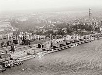 243_0861 Von den Abfertigungshallen der St. Pauli Landungsbrcken fhren Brcken hinunter zum Ponton; lks. der Eingang zum St. Pauli Elbtunnel mit der Kupferkuppel. Dahinter auf dem Elbhang die Navigationsschule, daneben das Hamburger Tropeninstitut - im Vordergrund liegen Schlepper am Anleger. Auf der rechten Bildseite hinter dem St. Pauli Fhrhaus und der Hochbahnstation Landungsbrcken das Gebude der Seewarte - der Kirchturm vom Michel ragt aus dem Hamburger Husermeer. 