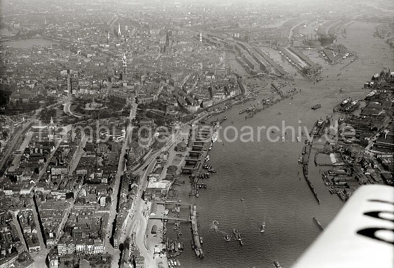 245_0333 historisches Luftaufnahme von Hamburg und den St. Pauli Landungsbrcken. In der linken Bildhlfte dei St. Michaeliskirche, rechts der Zollkanal an der Speicherstadt und der Sandtorhafen / Grasbrookhafen. Dahinter das Gasometer der Gaswerke auf dem Grasbrook und das Hafenbecken des Baakenhafens.  Luftbild von Hamburg / St. Pauli Landungsbrcken, Sandtorhafen Speicherstadt; 1931 - historische Hafenbilder aus dem Archiv der Hamburger Hafen und Logistik AG, HHLA. alte Hamburg Fotos als Geschenk fr Bro und Wohnung; Fotoleinwand + Posterprints.