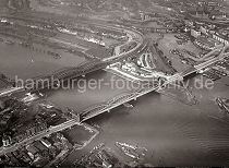 253_3767 Elbbrcken ber die Norderelbe; im Vordergrund unten lks. die Mndung des Marktkanals in Hamburg Veddel und auf der gegenber liegenden Seite der Elbe die Einfahrt zum Entenwerder Zollkanal und die lks. Zufahrt zum Billehafen und dem Oberhafen Kanal. Auf der linken Bildseite unter dem Oberhafen der Baakenhafen mit Frachtschiffen und Lagerschuppen.