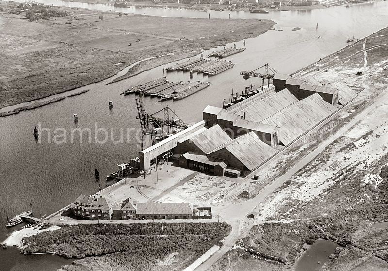 Historische Hamburgbilder aus dem Fotoarchiv der Hamburger Hafen und Logistik AG (HHLA)  Luftaufnahme Hamburger Hafen; Rethe, Kalikai + Reiherstieg; ca. 1929. 260_0874 Kaliumschlag an der Rethe/Kalikai; die Kalisalze wurden mit den Binnenschiffen angeliefert, die auf der Rethe an den Dalben ankern. Frachter liegen unter den Geiferanlagen, die das Kali lschen und per Frderband in die Lagerhallen transportiert werde. Im Hintergrund die Elbinsel Wilhelmsburg am Reiherstieg -  zwischen Rethe und Reiherstieg Weideland auf dem Pferde grasen.