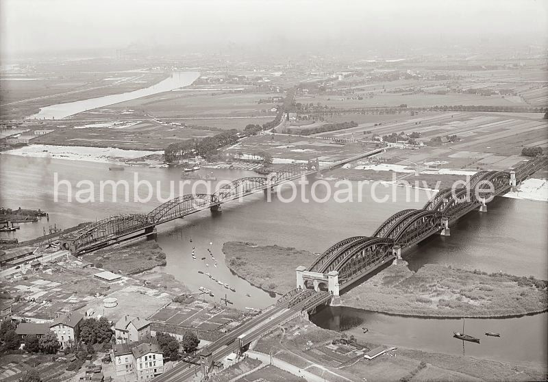 262_0545 BElbbrcken bei Harburg ber die Sderelbe - rechts die Eisenbahnbrcke und lks. die Strassenbrcke mit den beiden Sandsteinportalen. Lks. davon die Einfahrt zur Harburger Schleuse, die zum Harburger Hafen fhrt. Auf der anderen Elbseite im Hintergrund der Wasserturm von Wilhelmsburg und am Reiherstieg die Gebude der DIAMANT-MEHL Mhle. Am linken Bildrand die Reiherstiegschleuse.  Historische Hamburgbilder aus dem Fotoarchiv der Hamburger Hafen und Logistik AG (HHLA) Luftbild von der Sderelbe, Harburger Elbbrcken + Reiherstieg; ca. 1929