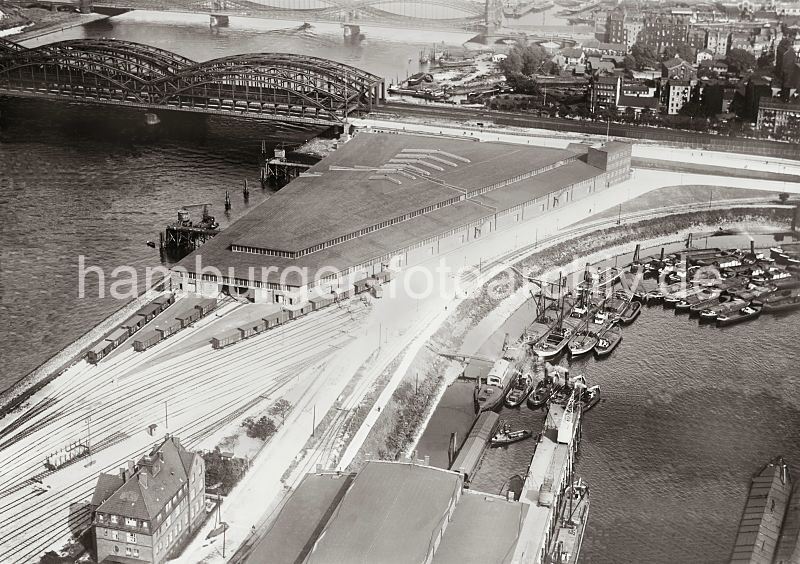 Luftfoto vom Verteilungszentrum Holhusenkai - Prager Ufer, Moldauhafen; ca. 1930 273_R_188_08 Luftbild Verteilungszentrum am Holthusenkai / Norderelbe - Gterzge stehen vor den Einfahrten in das dreieckige Hafengebude. Lks. im Hintergrund die Norderelbbrcken und Wohnbebauung auf der Veddel. Im Vordergrund Binnenschiffe und Schuten am Prager Ufer im Moldauhafen.