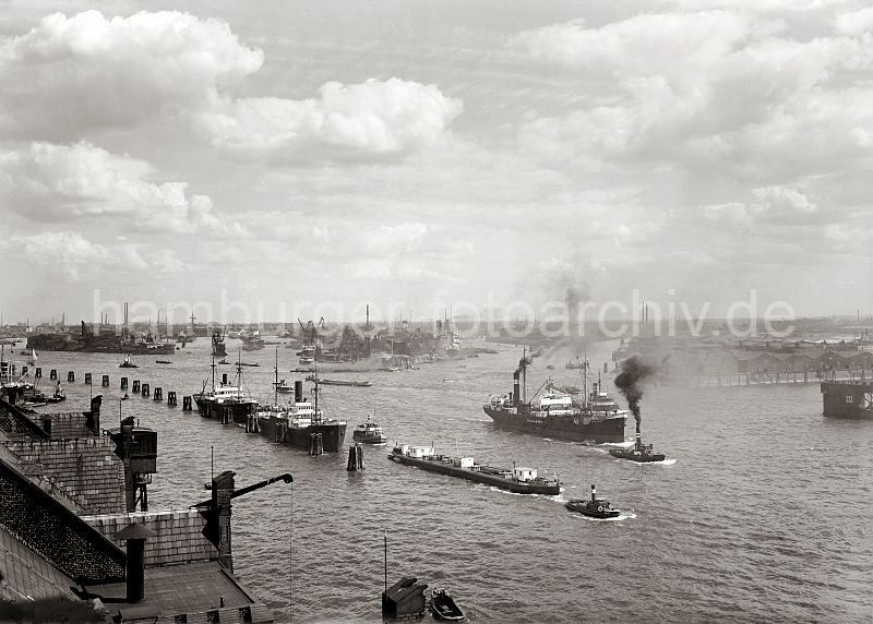 Alte Hamburg Fotos als Print oder Fotoposter / fotoleinwand - Kunstdruck. Blick ber die Norderelbe - Segelschiffhafen / Hansahafen / Sdwesthafen; ca. 1930. 283_0609 Blick vom Dach des Kaiserspeicher ber die Norderelbe auf den Hamburger Hafen. Vor dem Schiffbauer Hafen liegen Frachter an den Dalben; ein Tankschiff der FANTO lgesellschaft wird von einem Schlepper gezogen - dahinter ein Frachter, der mit Hilfe eines Hafenschlepper seinen Liegeplatz im Hamburger Hafen verlsst; Qualm steigt aus den Schornsteinen der beiden Schiffe. Rechts die Einfahrt zum Sdwesthafen, in der Bildmitte der Hansahafen und lks. das Hafenbecken des Segelschiffhafens.