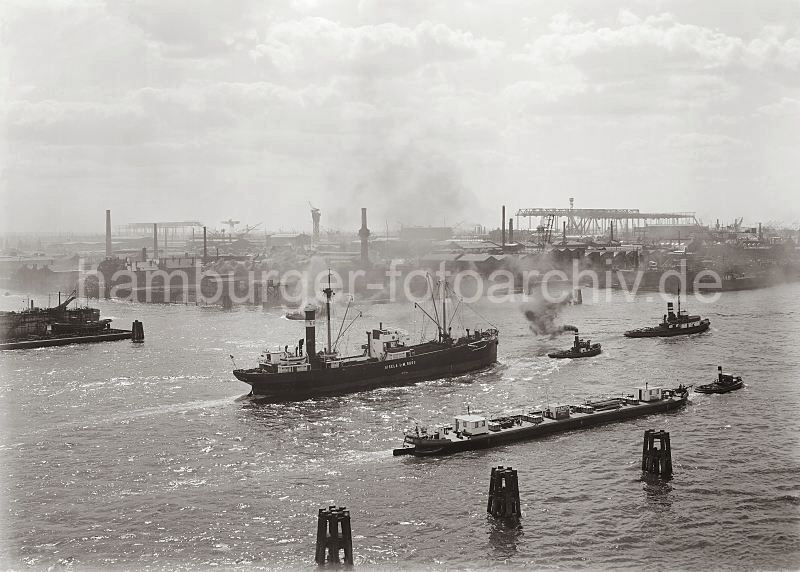 Werftanlagen der Deutschen Werft - Frachter mit Schlepper; ca. 1930 285_609a Blick ber die Norderelbe zu den Werftanlagen der  Deutschen Werft; im Vordergrund Holzdalben, ein Frachter wird mit einem Schlepper aus dem Hamburger Hafen gezogen. 