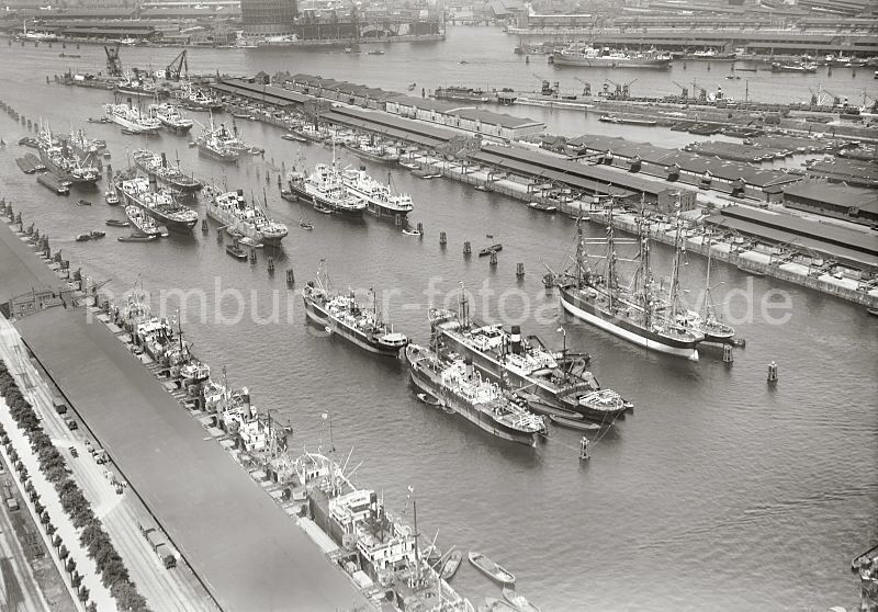 Luftbild vom Segelschiffhafen - Frachtschiffe an den Dalben; ca. 1930  287_1520 Frachterschiffe und zwei Frachtsegler liegen an den Dalben in der Mitte des Hafenbeckens vom Segelschiffhafen, bei einigen Schiffen wird die Fracht ber Schuten gelscht. In der rechten oberen Bildhlfte der Moldau Hafen mit dem Veddel Hft und dem Prager Ufer. Im Hintergrund neben dem Gaswerk die Einfahrt zum Magdeburger Hafen und rechts das Baaken Hft und der Kirchenpauer Kai.