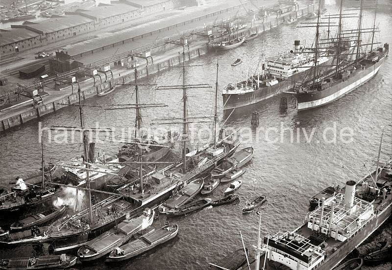 Luftbild vom Segelschiffhafen - Frachtsegelschiffe Pamir + Parma; ca. 1930 289_0013 Im Segelschiffhafen liegen die beiden Windjammer Pamir (lks.) und Parma - die Ladung des Frachtseglers Pamir wird gerade gelscht - Schuten liegen lngsseits des Segelschiffs. Rechts die Viermastbark Parma, daneben der Frachter Cuyaba - ein kleiner Dreimastsegler liegt am Asia Kai; seine Fracht wird in bereit stehende Gterwaggons gelscht.  