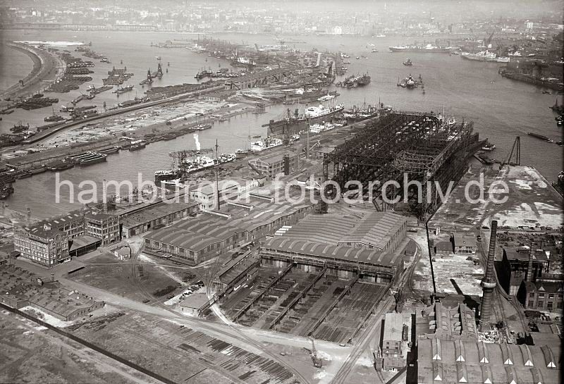 Luftfotografie Vulkanhafen - Kohleschiffhafen; ca. 1930 - 290_2502 Im Vordergrund das Gelnde der Howaldtswerft und der Vulkanhafen; am Vulkankai liegt das Schwimmdock mit einem eingedockten Frachter sowie weitere Frachtschiffe - am Ballinkai haben Schuten und Arbeitskhne fest gemacht, dahinter ist Kleingartengelnde zu erkennen, auf den Schrebergartenparzellen stehen Lauben. Im Kohleschiffhafen liegen die Kohleschuten dicht beisammen, in der Mitte des Hafenbeckens zwei schwimmende Kohleheber. 