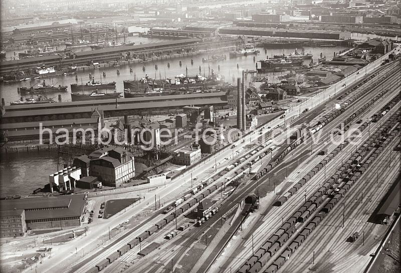 Luftfotografie Hafen Hamburg -  Kaiser Wilhelm Hafen, Kuhwerder Hafen; ca. 1931 294_2505 Luftfoto vom Hansahafen - lange Gterzge stehen auf den Gleisanlagen des Gterbahnhofs Hamburg Sd. Am India Kai des India Hafen die hohen Schornsteine einer Kokerei - dahinter der Bremer Kai und das Lbecker Ufer des Hansa Hafens. Hinter dem O'Swald Ufer die Lagerhuser des Saale Hafens und die Wohnblock auf der Veddel sowie der Kirchturm der Immanuelkirche. Auf der oberen linken Bildseite der Segelschiffhafen und die Durchfahrt zum Moldau Hafen - im Hintergrund die Elbbrcken.