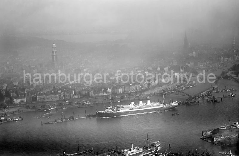 Luftbild von Hamburg - Passagierschiff Cap Polonio, berseebrcke; ca. 1930. alte Hamburgfotos als Geschenk zu Weihnachten, Geburtstag, Jubilaeum. 304_1019 Blick ber die Elbe auf den Passagierdampfer CAP POLONIO, der am Anleger an der berseebrcke fest gemacht hat.  Am Johannisbollwerk / Vorsetzen liegen Binnenschiffe und Frachter am Kai der Elbe Rhein Schuppen; lks. der Binnenhafen und Zollkanal. Davor die schwimmenden Arbeitshuser und Barkassen am Brandenburger Hafen. Im Hintergrund sind die Trme der St. Michaeliskirche, der St. Nikolaikirache und der St. Katharinenkirche zu erkennen.