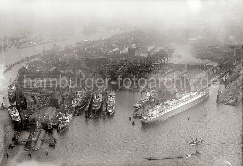 Luftfotografie der Werft Blohm & Voss - Schwimmdocks, Werfthelgen; ca. 1930. historische Hamburgfotos als Kunstdruck zum Geschenk zu Weihnachten, Geburtstag, Jubilaeum. 304_3_0038 Luftbild der Hamburger Werft Blohm & Voss auf Steinwerder - Frachter liegen an den Werftkais zur Reparatur - ein Frachtschiff wurde in einem Schwimmdock eingedockt. Im Werfthafen liegt das Passagierschiff Europa, daneben ein leeres Schwimmdock.