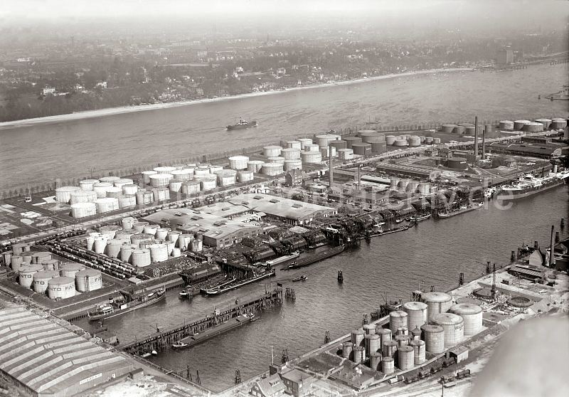 <title>Flugbild des Petroleumhafens + Elbe mit Oevelgoenne, Neumhlen; ca. 1931. historische Hamburgfotos als Fotoposter zum Geschenk zu Weihnachten, Geburtstag, Jubilaeum. 304_4_0939 Luftfoto des Hamburger Petroleumhafens auf Waltershof - am Kai liegen Tanker, ihre Ladung wird gelscht; An Land sind sind Benzin-Fsser aufgestapelt und warten auf den Abtransport. Auf vier Bahngleisen stehen zwischen den Tanklagern Tankwaggons der Eisenbahn - am gegenber liegenden Elbufer ist der Elbstrand von Oevelgoenne zu erkennen; rechts das Khlhaus von Neumhlen.