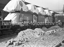 435_11 Autotransport auf Gterwaggons in den Hamburger Hafen; die Volkswagen stehen zum Schutz mit Planen abgedeckt auf Waggons auf einer Kaianlage im Oderhafen, einem der zahlreichen Hafenbecken im Hamburger Hafengebiet. Im Hintergrund der Ausleger einer Krananlage, die sich ber den Bahngleisen befindet. Bauarbeiten auf dem Hafenkai, die Strasse zwischen den Gleisen wird mit Pflastersteinen neu gepflastert.  