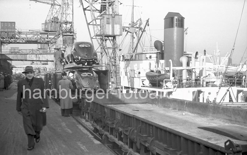 historische Hafenbilder aus dem Archiv der Hamburger Hafen und Logistik AG (HHLA)  436_10 Die Schutzplanen sind von den Volkswagen entfernt - die Brezelkfer mit ihren geteilten Heckscheiben stehen auf zwei Ebenen der Gterwaggons. Die Wagen werden kontrolliert und fr die Verschiffung vorbereitet - das Frachtschiff liegt am Kai; mit dem Kran sollen die Kraftfahrzeugen an Bord gebracht werden.