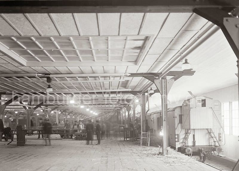 474_698a DEisenbahnwaggons, die auf dem Gleis im Fruchtschuppen stehen werden mit Bananen beladen. Die Sdfrchte werden aus dem Lager mit Frderbndern transportiert - Arbeiter kontrollieren die Qualitt der Ware. Altes  Bild von der Arbeit im Hafen Hamburgs, Bananen - Verladung; ca. 1932. Fotos von der Geschichte Hamburgs - Arbeit im Hafen Hamburgs.</title>
