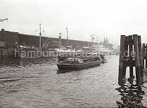 496_791 Eine Schute, die teilweise mit Scken beladen ist, wird von einem Schlepper durch ein Hafenbecken im Hamburger Hafen gezogen. Frachter liegen am Kai und werden ber Kaikrane, die auf Schienen laufen, be- und entladen. Rechts Holzdalben, sogen. Duckdalben, an denen Schiffe in der Mitte des Hafenbeckens festmachen knnen, um die Ladung dort ber Schuten zu lschen. 