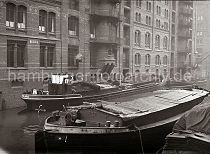 497_B_342 Lastkhne im Wandrahms Fleet der Speicherstadt Hamburg. Die Ladung eines der Binnenschiffe wird gelscht - eine Hieve Scke wir ber eine Winde auf einen der Lagerbden des Speicherblocks S gebracht. Im Hintergrund re. das Verbindungsfleet zum Zollkanal. 