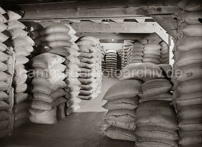 gestapelte Kaffeescke auf einem Lagerboden der Speicherstadt Hamburg; ca. 1938. Alte Hamburg-Bilder als Fotodruck oder auf Fotoleinwand. 503_507a Bis unter die Decke des Lagerbodens sind Kaffeescke in einem Lagergebude der Speicherstadt gestapelt. 1885 wurde mit der Planung zum Bau der Hamburger Speicherstadt begonnen. Es entstand unter der Leitung des zustndigen Oberingenieurs Franz Andrea Meyer in neogotischer Architektur auf einer Gesamtflche von 630 000 der grte zusammenhngende Lagerkomplexes der Welt. Betrieben wurden die Speichergebude von der HFLG, der Hamburger Freihafen-Lagerhaus-Gesellschaft, aus der 1935 nach dem Zusammenschluss mit der Hamburger Kaiverwaltung die Hamburger Hafen- und Lagerhaus Aktiengesellschaft entstand.