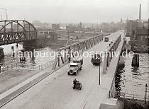 532_743a Blick ber den Reiherstieg vom Kleinen Grasbrook nach Steinwerder; mit Fssern beladene Lastwagen, Fahrradfahrer und ein Motorrad mit Beiwagen berqueren die Reiherstiegbrcke. Links die Eisenbahnbrcke ber den Reiherstieg, dahinter Gebude der Ellerholzschleuse, die in den Oderhafen und Travehafen fhrt. Ganz lks. Schornsteine des HEW Elektrizitts-Werks an der Nippoldstrasse.