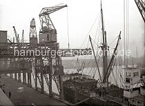 542_182 Ein Frachter liegt am Schuppen 82 des Chilekais im Oderhafen, eines der vielen Hafenbecken im Hamburger Hafen. ber einen Dreifachkran werden grosse Frachtkisten an Bord des Schiffes gebracht. Im Hintergrund die Kaischuppen am Mnckebergkai des Ellerholzhafens. Alte Hamburg- bilder aus dem Hafen