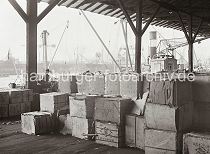 570_652a Kisten mit Kautschuk mit der Aufschrift Smoked Sheet sind  in dem Lagerschuppen gestapelt. Auf anderen Holzkisten steht der Ursprungsort Liverpool. Im Hintergrund sind auf der anderen Seite der Elbe die Werftanlagen der Deutschen Werft zu erkennen.