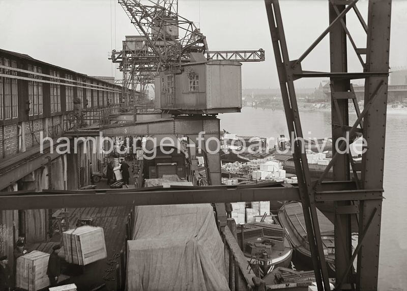 Historische Hamburgbilder aus dem Fotoarchiv der HHLA. Halbportalkran am Sdwesthafens - Gueterumschlag im Hafen der Hansestadt Hamburg. 581_646 Blick von einem Halbportalkran auf den Gterumschlag im Hamburger Hafen - groe Kisten werden ber die an der Laderampe stehenden Gterwaggons verladen. An der Kaimauer vom Hafenbecken des Sdwesthafens liegen mit Gter beladene Schuten.