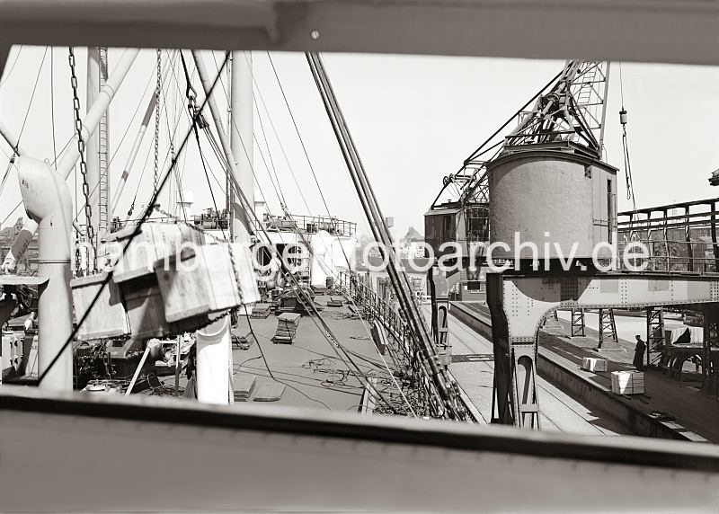 Historische Hafenbilder aus der Hansestadt Hamburg. Ladung lschen eines Frachtschiffs im Hamburger Hafen / Indiahafen, Australiakai - Kisten am Kranhaken.  584_661 Arbeit im Hafen der Hansestadt Hamburg; ein Frachtschiffs wird entladen - Holzkisten hngen von einer Eisenkette zusammengehalten an dem Kranhaken und werden an Land gebracht. Auf der Laderampe des Hafenkais stehen schon abgeladene Kisten, die auf ihren Weitertransport in den Lagerschuppen warten.