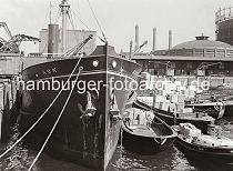 603_672 Der britische Frachter AUK liegt am Dalmannkai des Hamburger Grasbrookhafens. Hafenkrane lschen die Ladung des Frachtschiffs - auf der Wasserseite wird ber einen bordeigenen Ladebaum eine Hieve Kartons auf eine lngsseits liegende Schute geladen. Im Hintergrund rechts ein Ausschnitte des Gasometers vom Gaswerk Grasbrook, links das vom Hamburger Oberbaudirektor Fritz Schumacher entworfene Heringskhlhaus.