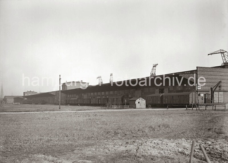 Historische Hamburgmotive aus dem Archiv der Hamburger Hafen und Logistik AG HHLA. Gterzug an der Laderampe des Schuppen 60, Kamerunkai des Sdwesthafens; ca. 1932.  620_641a Blick zur Landseite des Verteilungsschuppen 60 - Gterwaggons stehen an der Laderampe des Hafenschuppens. In einer kleinen Bretterbude mit Schornstein ist der Pfrtner der Kaiverwaltung untergebracht, ein Schild unter dem Dach weist darauf hin. Hinter dem Gebudes ragen die Ausleger der Kaikrane empor - ganz links ist der Kirchturm der St. Nikolai kirche zu erkennen.