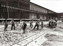 622_12_B_203a Der Hafenkai am Kaischuppen 58 wird gebaut; Bauarbeiter schaufeln Sand - drei Mnner schieben auf provisorischen Gleisen eine mit Sand gefllte Lore der Laderampe entlang. 